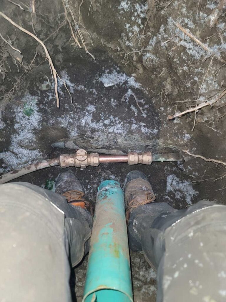 Plumber repairing frozen pipe outdoor in winter