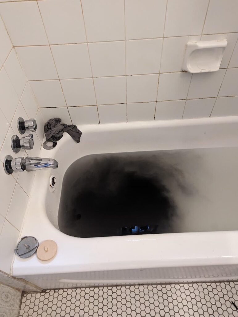 Clogged Bathtub with Black Water and Debris